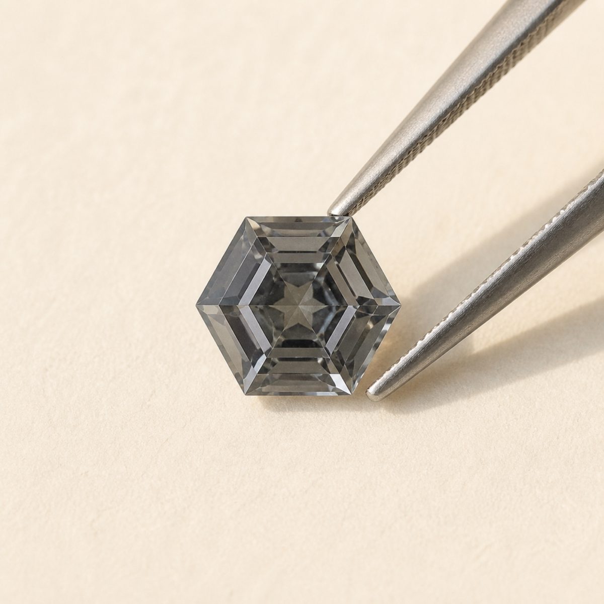 Gray spinel · No. 121 held in tweezers on ivory paper